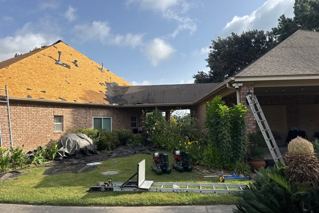 Roof tear-off in progress exposing the decking on a storm-damaged brick Texas home