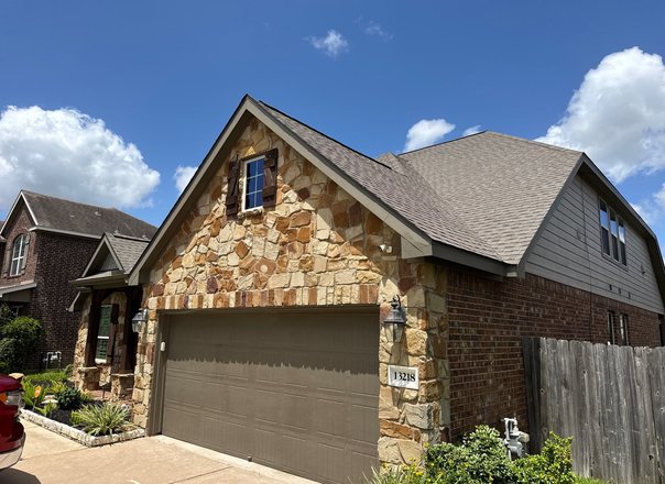 Stone gable Texas home with a newly installed architectural shingle roof and gutters